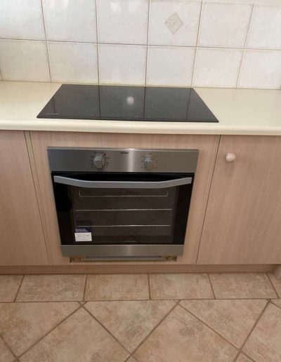 A white underbench oven & solid hot plate replaced with a Stainless Steel oven with stainless steel trim at the bottom & ceramic cooktop